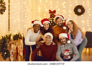 Group portrait of smiling multiethnic friends in Santa hats pose together for New Year picture. Happy diverse international young people celebrate Christmas in decorated home. Winter holidays. - Powered by Shutterstock