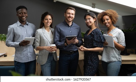 Group Portrait Of Smiling Multiethnic Millennial Work Team Standing Together Looking At Camera In Office, Happy Young Multiracial Diverse Colleagues Posing For Picture Show Unity And Partnership