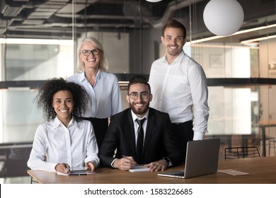 Group Portrait Of Smiling Multiracial Businesspeople Stand Posing In Modern Office Look At Camera, Happy Diverse Multiethnic Colleagues Laugh Make Picture Together Show Unity And Business Loyalty