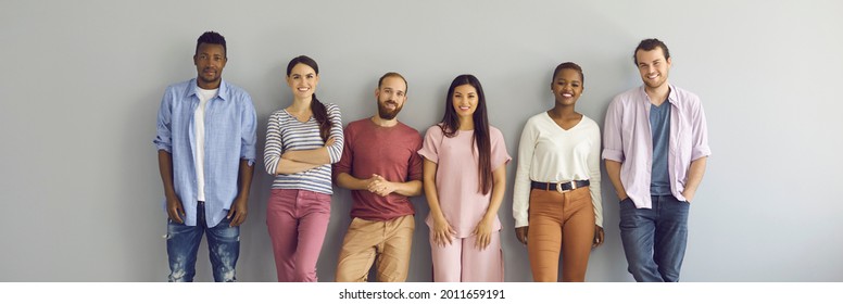 Group Portrait Of Smiling Young Models In Comfortable Casual Everyday Natural Color T Shirts And Jumpers. Happy Diverse People Posing Against Light Grey Studio Wall. Banner. Clothes, Fashion Concept