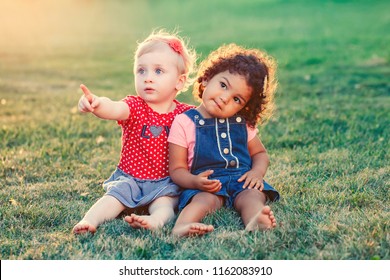 Group portrait of two cute adorable girls toddlers children sitting together. White Caucasian and latin hispanic babies hugging outside in park. Friendship and best friends forever concept.  - Powered by Shutterstock