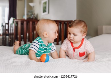 Group portrait of two white Caucasian cute adorable funny baby boys lying together on bed communicating and playing. Friendship childhood concept. Best friends forever. Children talking