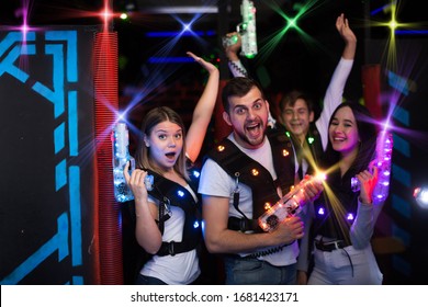 Group portrait of young people in colorful beams of laser guns having fun on lasertag arena
