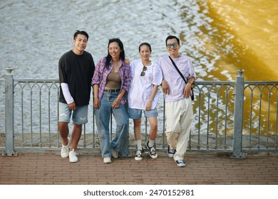 Group posing casually by the riverside fence, displaying friendship