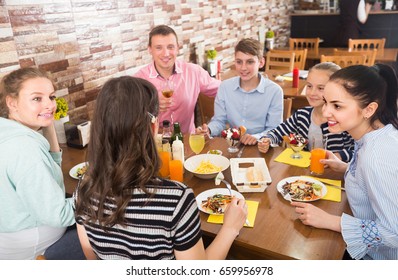 Group Of Positive American Adults And Teenagers Spending Time In Family Cafe