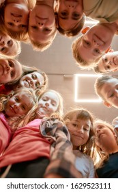 Group Of Positive Boys And Girls With Their Female Dance Teacher. Bottom View Of Happy Children Smiling At Camera While Standing In The Dance Studio. Friendship