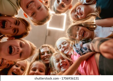 Group Of Positive Boys And Girls With Their Female Dance Teacher. Bottom View Of Happy Children Smiling At Camera While Standing In The Dance Studio. Friendship