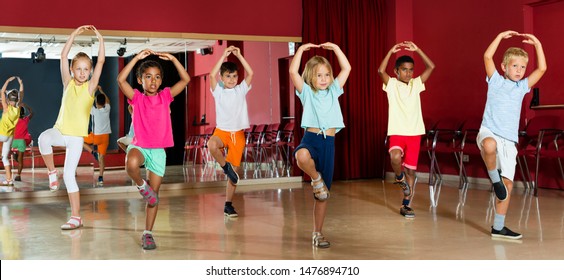 Group of positive childrens trying balance movements of ballet at classroom 