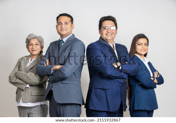 Group of positive\
indian business partners wearing suit standing cross arms looking\
at camera with smiles isolated on white studio background. Asian\
corporate people.