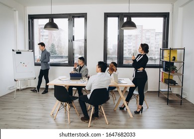 Group Of Positive Multicultural Marketing Experts Planning Working Process And Sharing Ideas While Creating Advertising Campaign.Young Colleagues Collaborating Together In Loft Interior Office