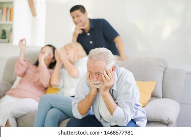 Group Of Positive Seniors European And Asia Are Sitting On The Big Sofa And Talking Which Looking Television At Retirement Home. Retired Old People Are Felling Sad.