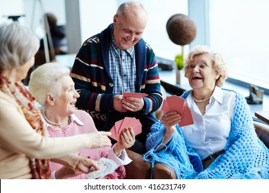 Group of positive seniors playing cards