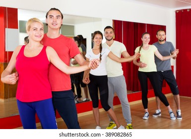 Group of positive smiling  adults dancing salsa in club