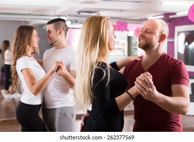 Group Of Positive Smiling Young Adults Dancing Salsa At Dance Class