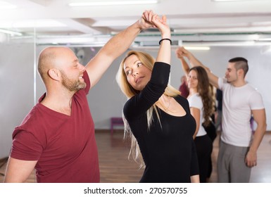 Group Of Positive Smiling Young Adults Dancing Salsa In Club