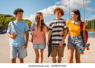 Group of positive teenagers high school pupils friends classmates college students boys and girls with bags skateboards walking in urban street hanging out together talking speaking with each others - Powered by Shutterstock