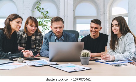 Group Of Positive Young Colleagues Sharing With His Boss New Ideas About Startup. Buisness People Having Discussion In Modern Loft Office. Front View.