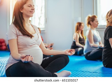 Group of pregnant women meditating on yoga class in lotus posture