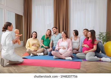 Group of pregnant women with men and doctor at courses for expectant parents indoors - Powered by Shutterstock