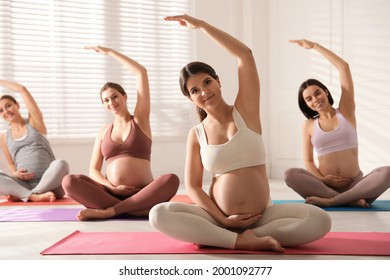 Group of pregnant women practicing yoga in gym