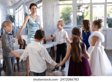 Group of preteen pupils in sunlit choreography studio partaking in circle dance, led by friendly elementary female teacher.. - Powered by Shutterstock