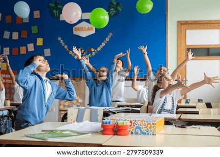Group of primary school students having fun during an interactive classroom activity with balloons.