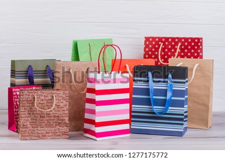 Group of printed paper shopping bags. Assortment of paper carrier bags with printing, horizontal image. Sale, consumerism, advertisement and retail.