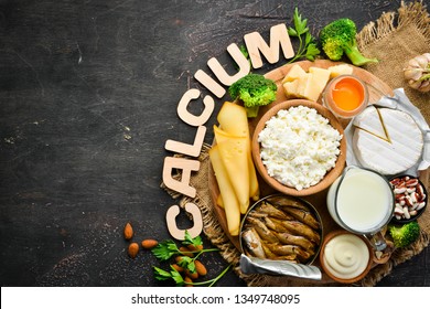 Group of products rich in calcium. Healthy diet food: cheese, milk, parmesan, sour cream, fish, almonds, parsley, garlic, broccoli. On the old background. Top view. Free copy space.