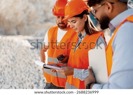 Group of professional construction checking plans and data at quarry site holding documents, copy space. Teamwork concept