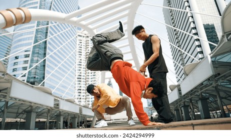 Group of professional happy street dancer cheer up while asian hipster perform b boy dance at urban city surrounded by people with low angle camera. Break dance concept. Outdoor sport 2024. Sprightly.