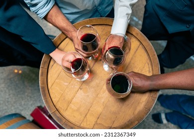 Grupo de profesionales sumilleres degustando y oliendo vino tinto en vitrocerámica en bodega con barril de madera en fábrica de vino. Industria de la producción de licor de invierno y concepto de negocio de la viticultora.