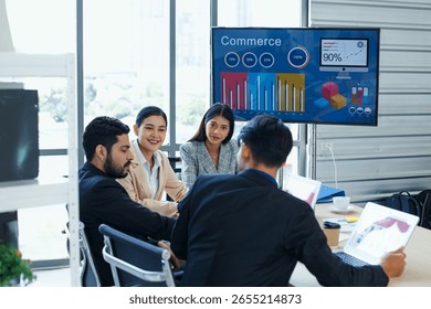 Group of professionals analyzing e-commerce data on digital screen during business meeting in modern office, showing teamwork, focus, and use of technology in corporate setting.
