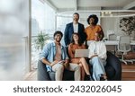 Group of professionals in business casual attire collaborating happily on a laptop in a modern office. Their teamwork and professionalism contribute to their success in this creative workspace.