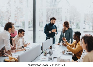 A group of professionals collaborating and working together in a modern office. They are discussing project solutions and working on paperwork. The team looks happy, successful, and focused. - Powered by Shutterstock