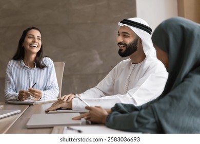 Group of professionals engaged in positive, collaborative meeting. Arabian businessman dressed in traditional attire lead negotiations with shareholders, clients or investors. Deal, success, business