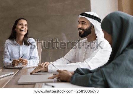 Group of professionals engaged in positive, collaborative meeting. Arabian businessman dressed in traditional attire lead negotiations with shareholders, clients or investors. Deal, success, business