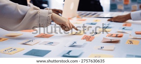 A group of professionals engages in a collaborative brainstorming session, using colorful sticky notes for idea generation and strategy planning at a modern office desk. SACTR