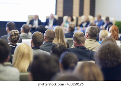 Group Of Professionals At The Round Table During The Conference. Speaking In Front Of Large Group Of People. Horizontal Image Composition