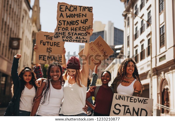 Group of protesters enjoying during a women\'s\
march with signboards. Laughing women holding protest signs for\
women power and future