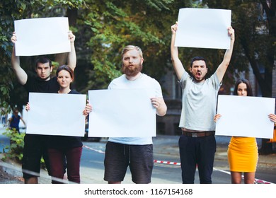 Group of protesting young people outdoors. The protest, people, demonstration, democracy, fight, rights, protesting concept. The caucasian men and womem holding empty posters or banners with copy
