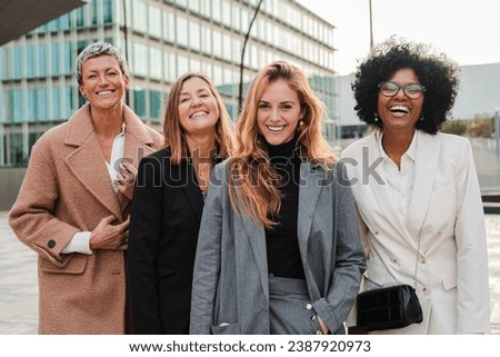 Group of proud businesswomen smiling and looking at camera at workplace. Real executive women staring front, laughing together with suit and successful expression. Corporate female employees meeting