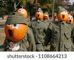 A group of pumpkins with painted faces are dressed up in army uniforms. 