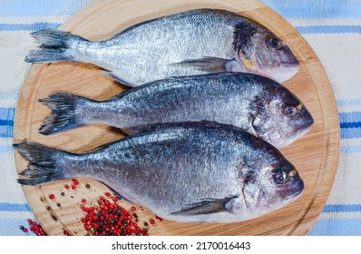 Group Of Raw Fish Prepared For Cooking On Cutting Board At Wooden Table. Healthy Seafood That Gives A Lot Of Energy At Home. Delicious Family Breakfasts, Lunches And Dinners.