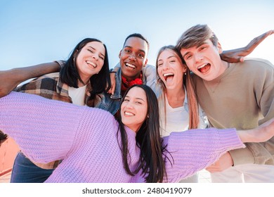 Group of real multiracial teenagers having fun together and posing for a portrait. Young friends smiling and laughing. Multiethnic people bonding outside with positive and friendly expression. High