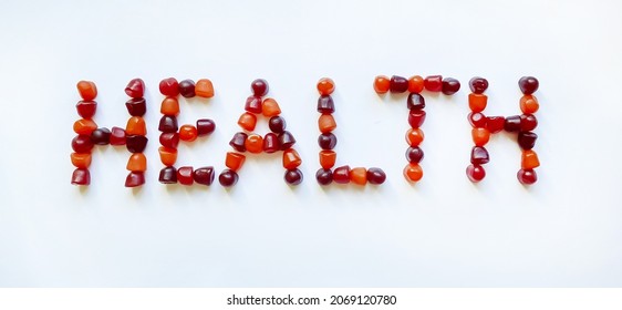 A Group Of Red, Orange And Purple Multivitamin Gummies Laid Out In The Form Of The Word Health