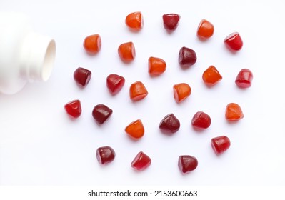Group Of Red, Orange And Purple Multivitamin Gummies With The Bottle Isolated On White Background. 