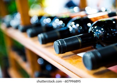 Group of red wine bottles stacked on wooden racks.