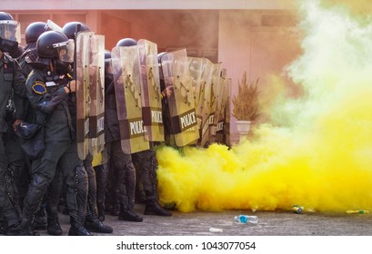 Group Riot Police With Protective Gear And Shields Surrounded By Tear Gas And Yellow Color Smoke Bomb In Tactical Training