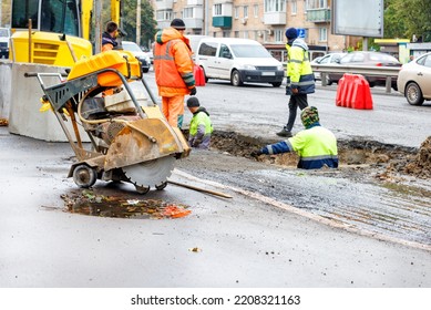 A Group Of Road Workers Repair Sewer Storm Hatches And Change Old Concrete Manholes For New Ones On A Roadway On An Autumn Day.