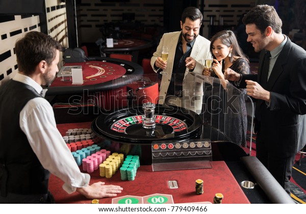 Group of\
roulette players placing their bets and waiting for the wheel to\
stop while having a good time in a\
casino